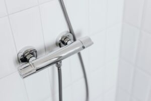 Modern chrome shower faucet on white tiled wall, elegant and clean design.